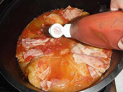 ダッチオーブンの中でキャベツのトマト煮にトマトケチャップがかけられています。