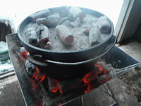 炭火の上にダッチオーブンが乗せられてさらに蓋の上にも火のついた炭が乗せられています。炭火がきれいです。