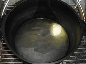 炭火で温められたダッチオーブンの中でバターが溶けています。