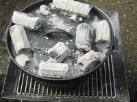 ダッチオーブンが蓋の上から炭火で加熱されています。