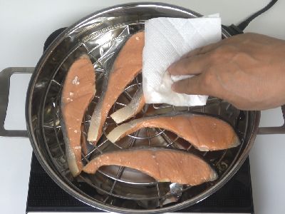 燻煙中、塩鮭の表面の水滴を拭き取ります。